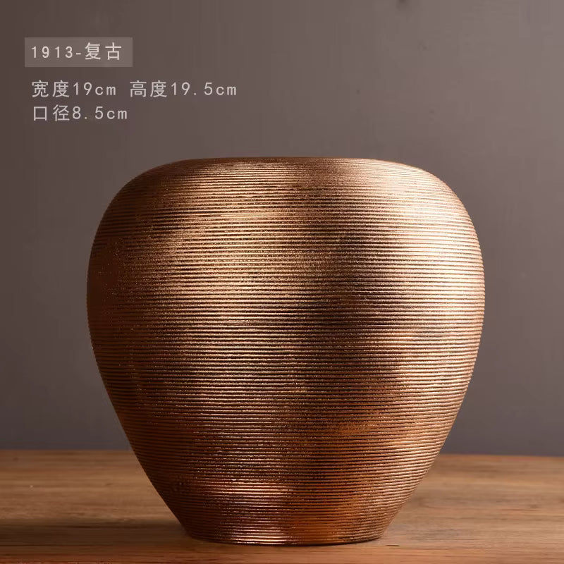 Bronze-colored vase with textured surface on a wooden surface against a dark background