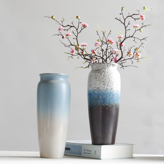 Two ceramic vases with gradient colors and a decorative branch with flowers on a light gray background.