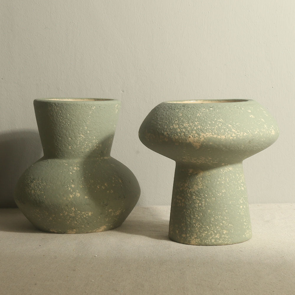 Two green ceramic vases on a neutral background