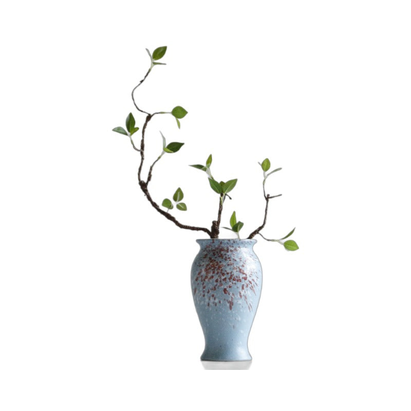 Blue ceramic vase with decorative branches on a white background