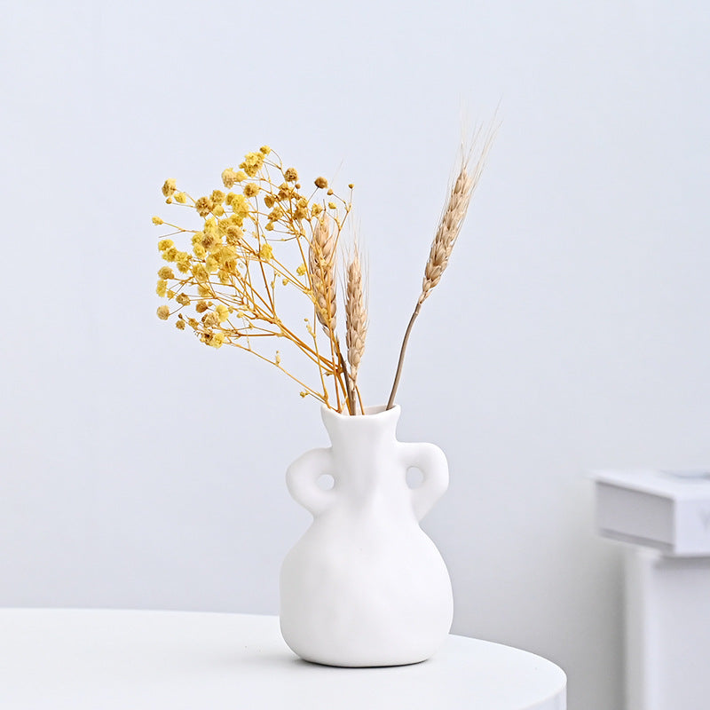 White vase with yellow dried flowers on a light gray background