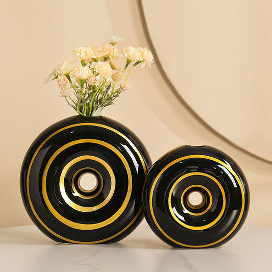 Two black vases with gold circular patterns on a beige background