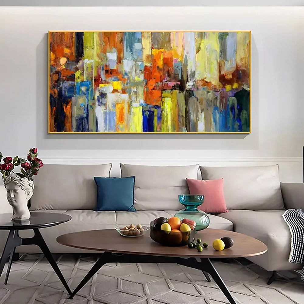 Living room with a large abstract painting above a sofa, coffee table with fruit, and decorative items.