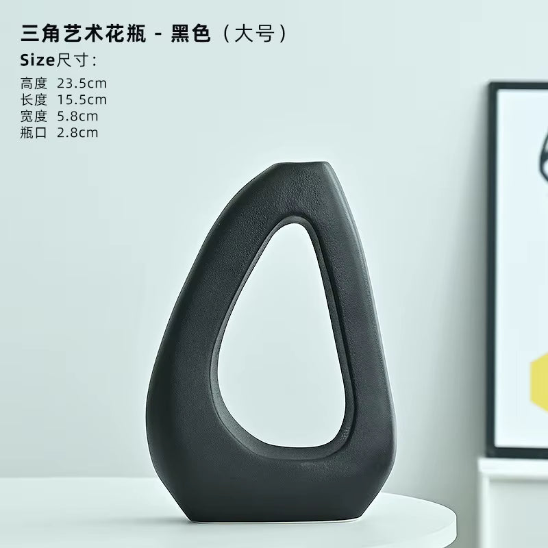 Black artistic vase on a white surface with product details in the background