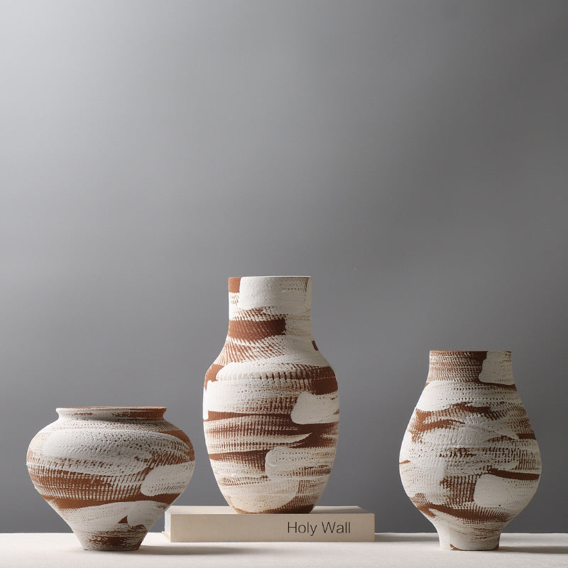 Three ceramic vases with brown and white patterns on a gray background