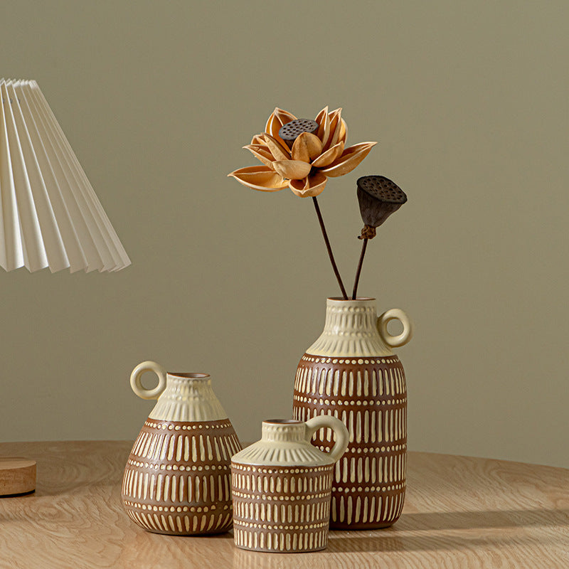 Three ceramic vases with decorative patterns on a wooden surface against a plain wall.