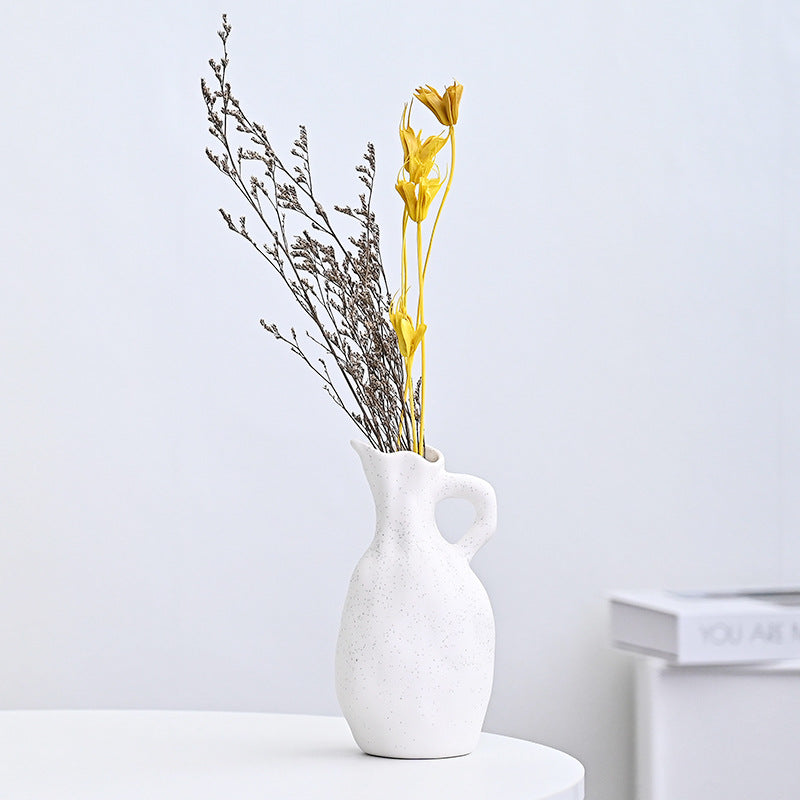 White ceramic vase with dried flowers on a light gray background