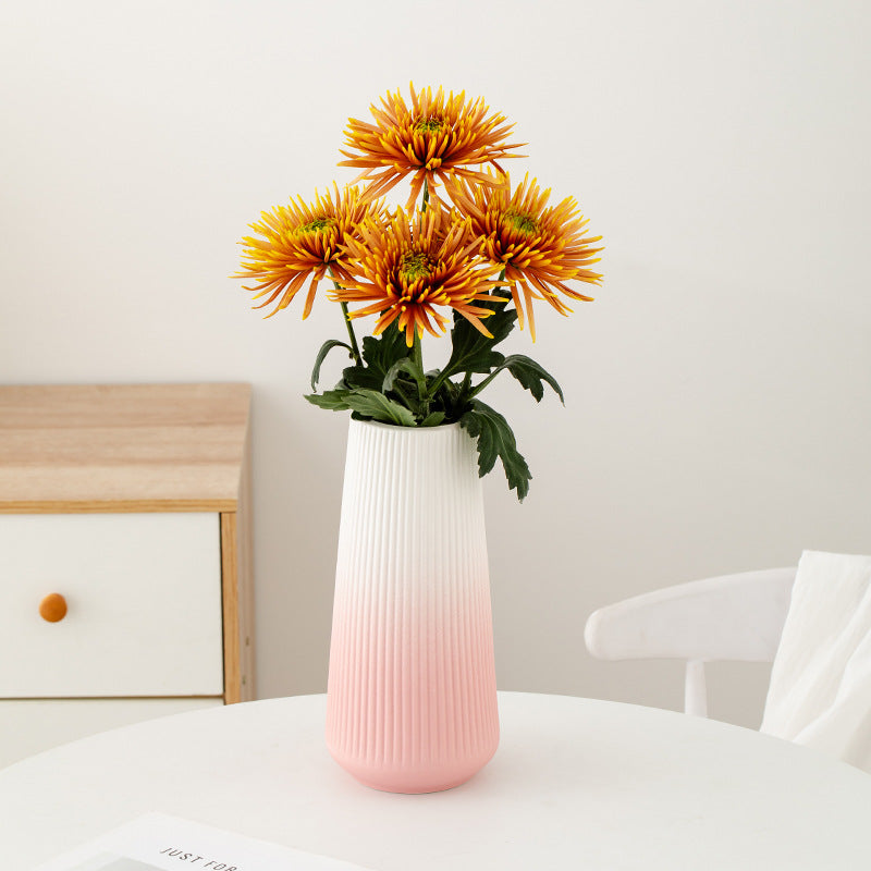 White and pink vase with orange flowers on a table