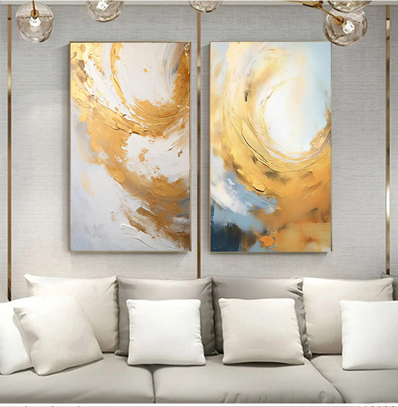 Two abstract art pieces hanging above a sofa with white cushions.