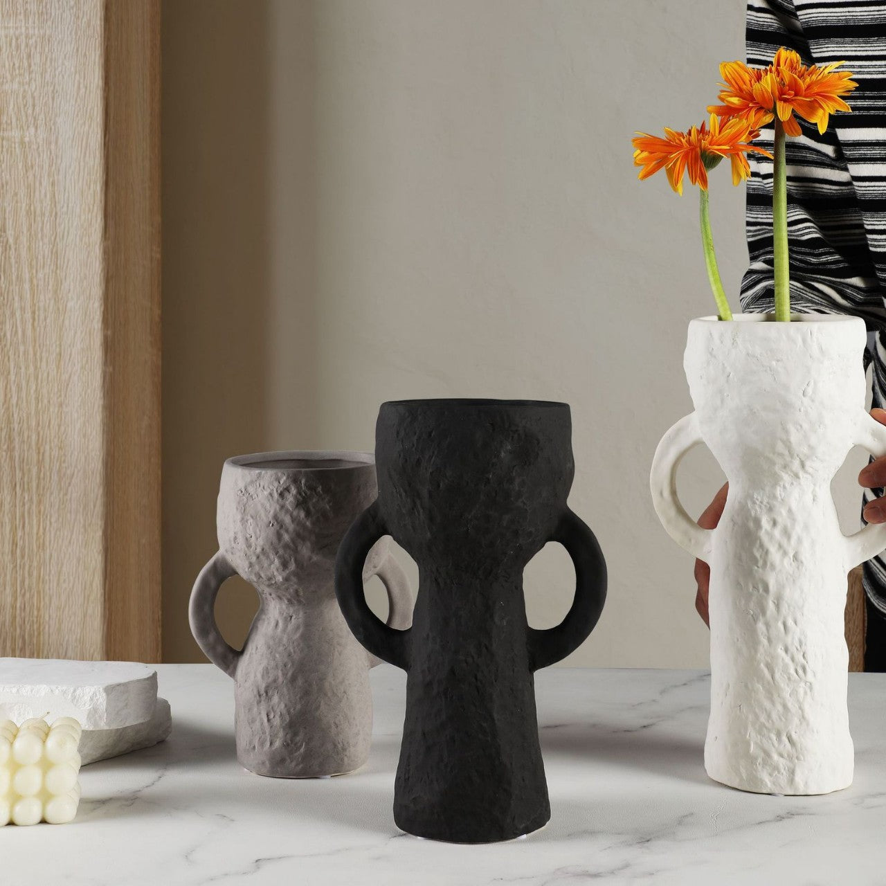 Three unique vases on a marble surface with a neutral background