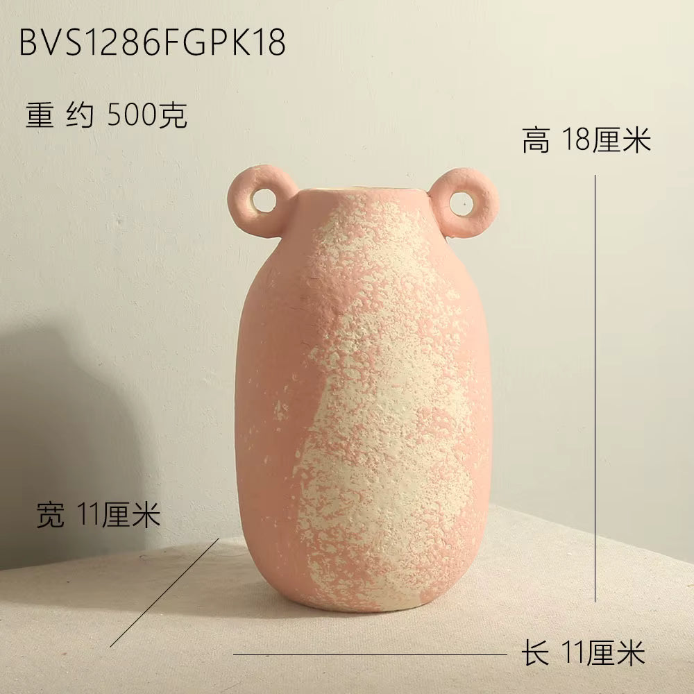 Pink ceramic vase with two small handles on a light gray background