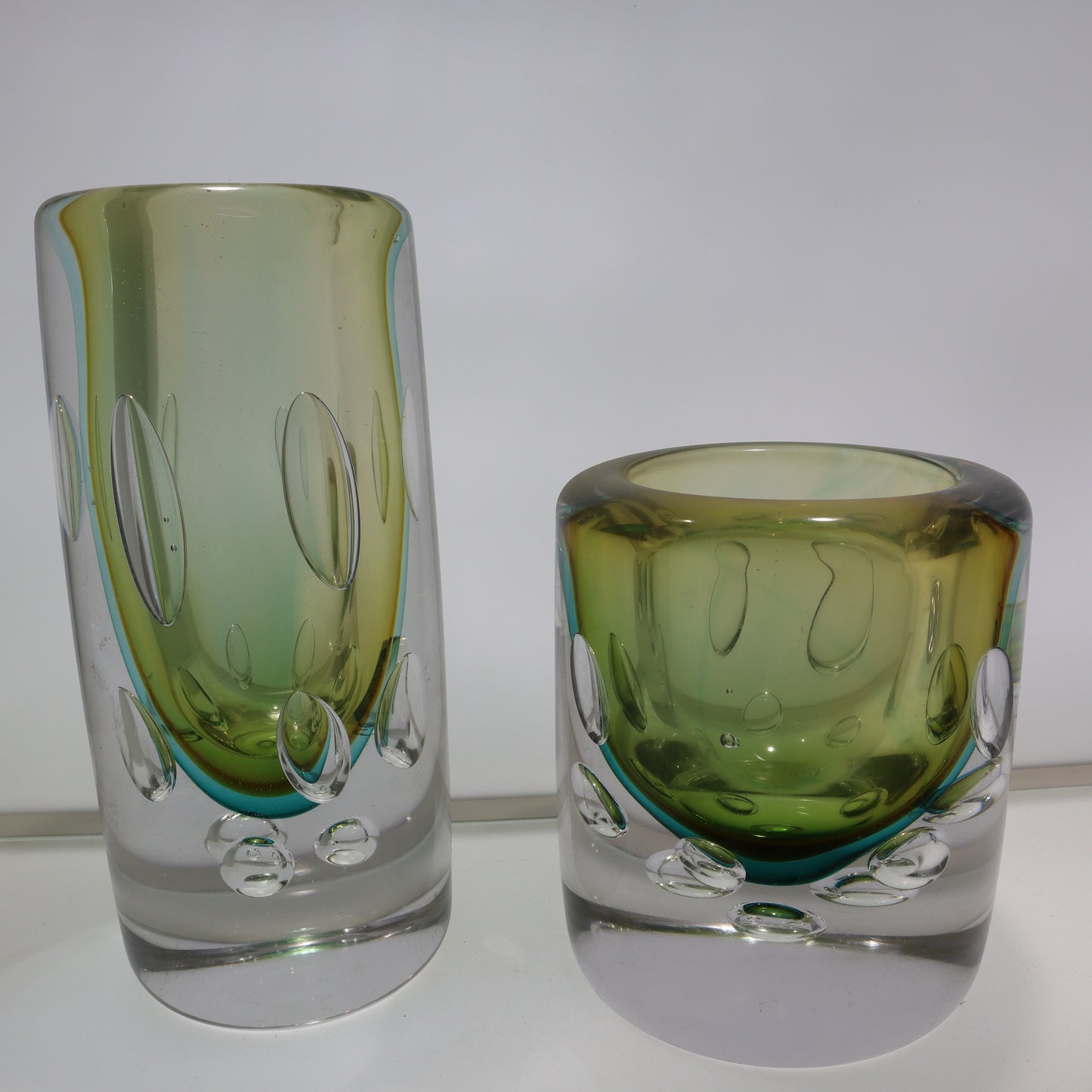 Two green glass tumblers on a white background