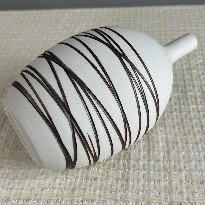 White vase with black stripes on a textured surface