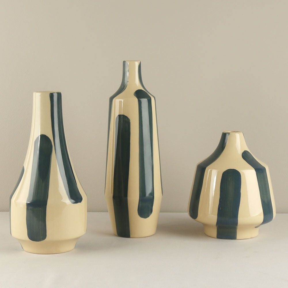 Three ceramic vases with green accents on a beige background