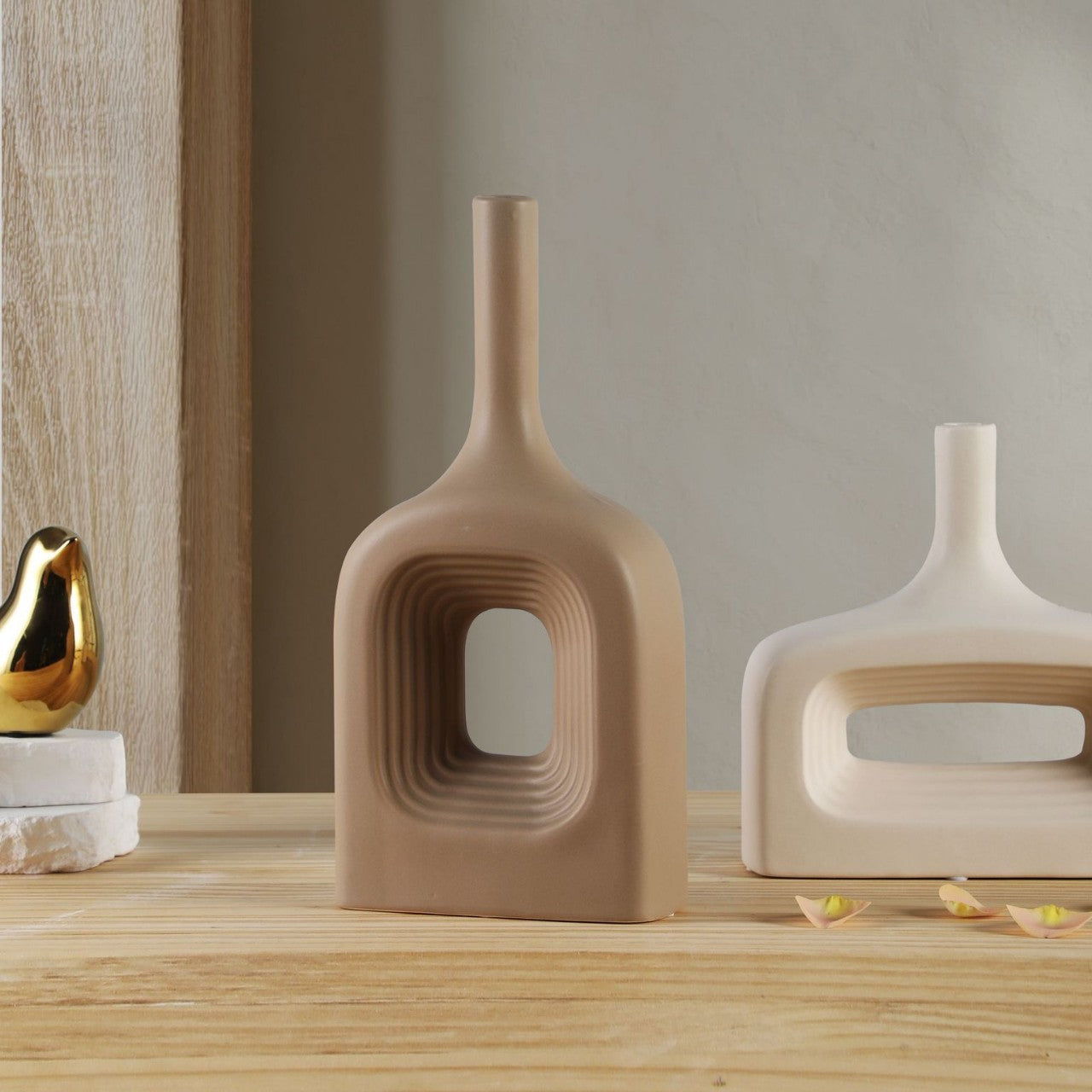 Two modern ceramic vases on a wooden surface with a neutral background