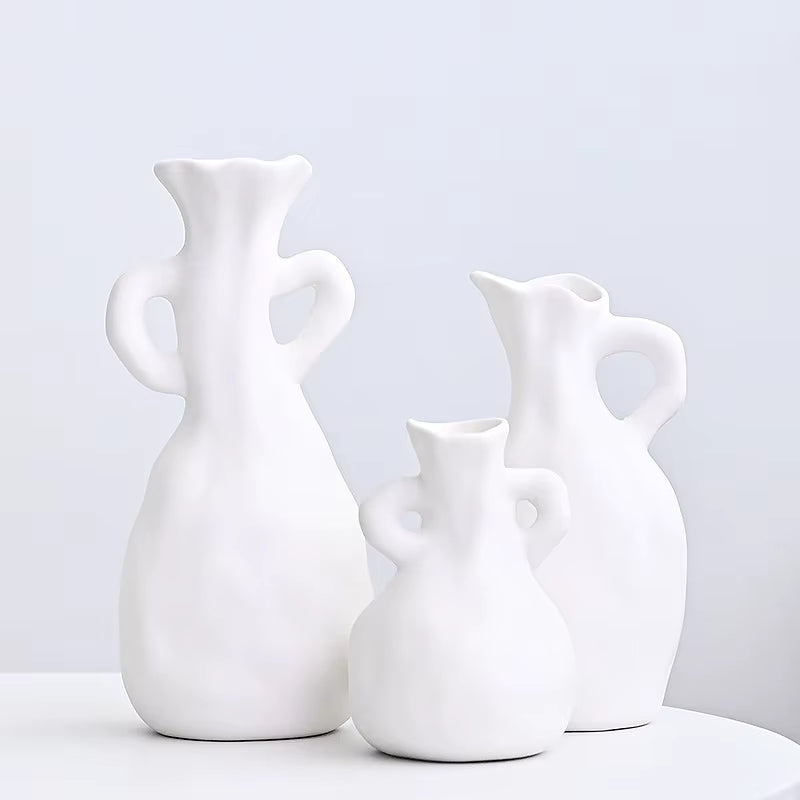 Three white ceramic vases of different shapes on a light gray background