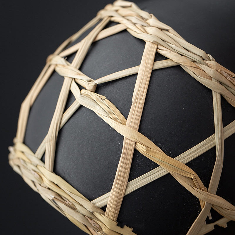 Black sphere with woven beige straw pattern on a black background