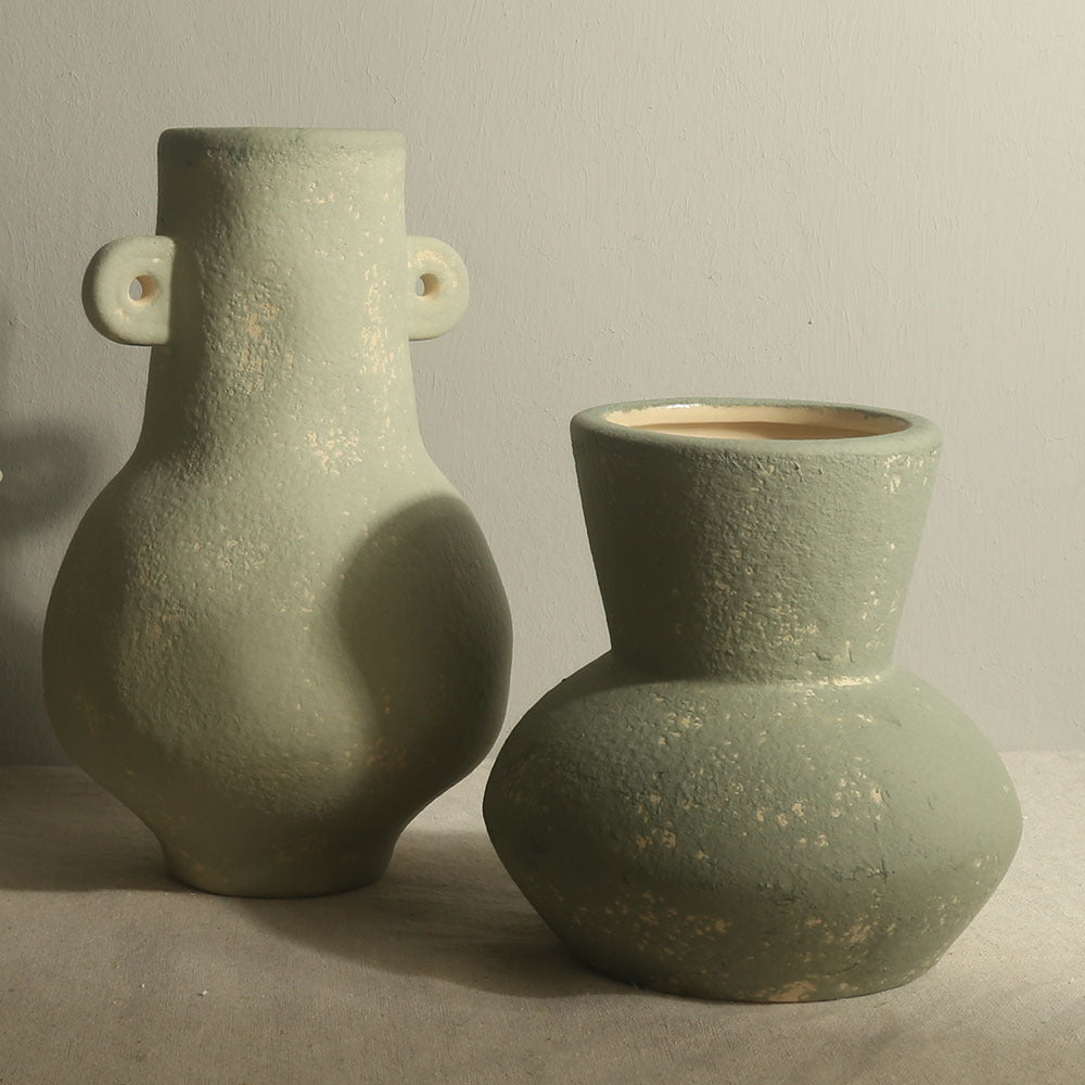Two green ceramic vases on a neutral background
