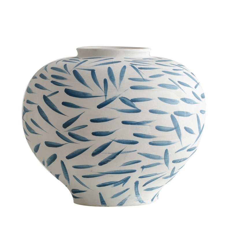 White vase with blue leaf pattern on a white background