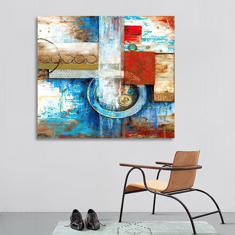 Abstract painting with geometric shapes on a wall above a chair and shoes.
