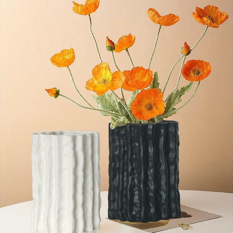 Two textured vases, one black and one white, with orange flowers on a beige background.