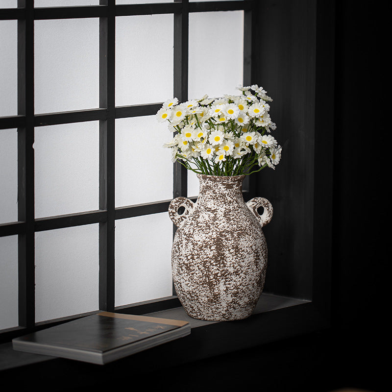 Decorative vase with flowers on a shelf against a black and white window pane background
