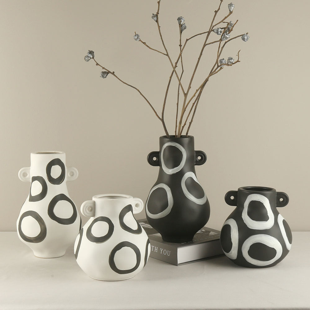 Set of four black and white patterned vases on a neutral background