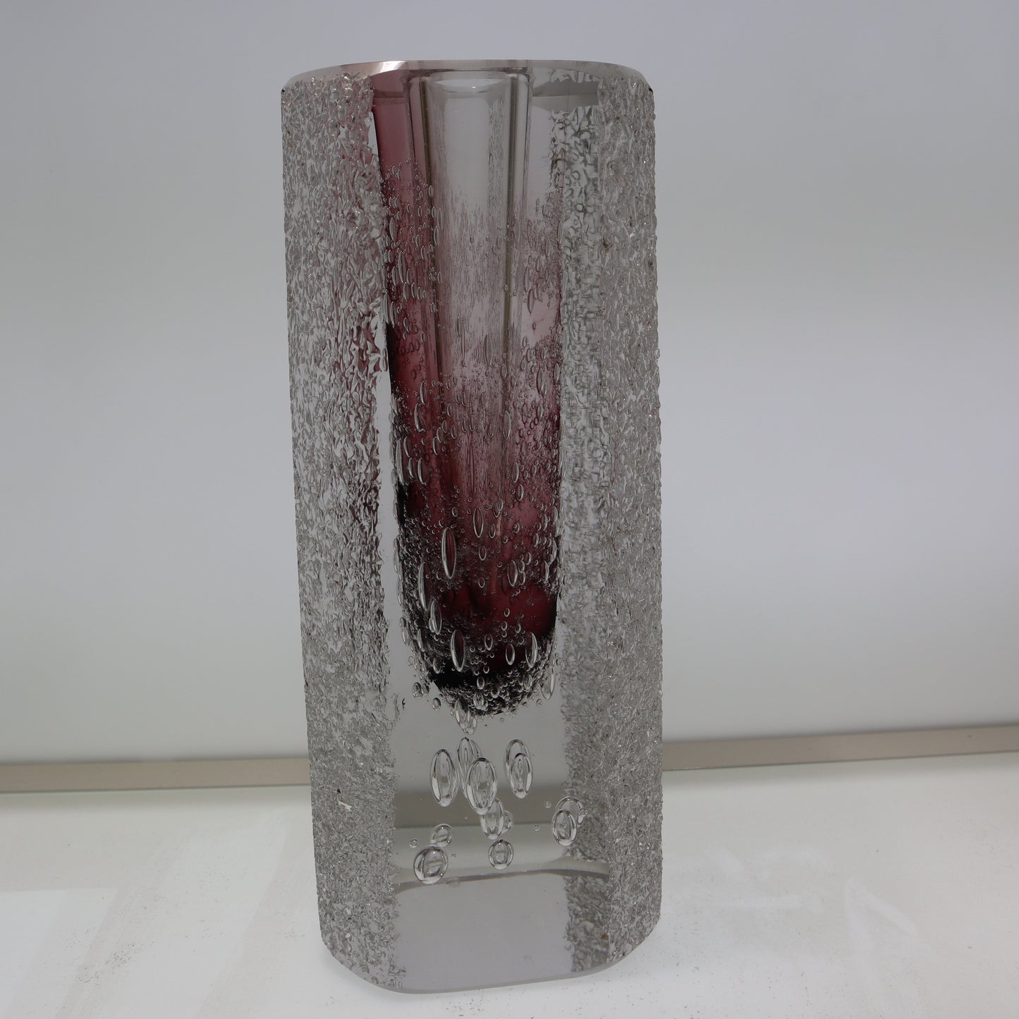 Decorative glass vase with textured silver base and purple interior on a white background