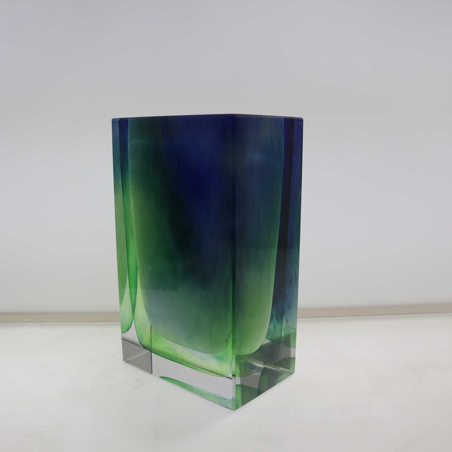 Green and blue glass vase on a white background