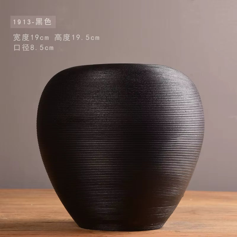 Black textured vase on a wooden surface with a gray background