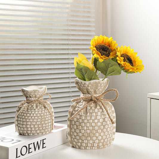 Decorative woven vases with sunflowers on a surface with a LOEWE book in the background.