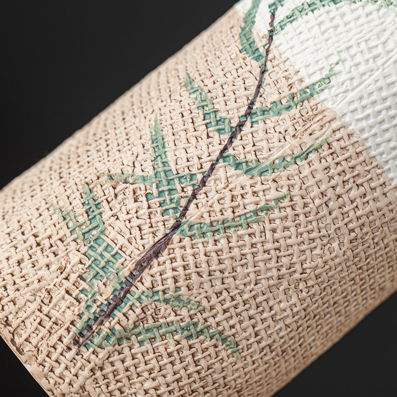 Close-up of a woven fabric with embroidered green leaves on a dark background