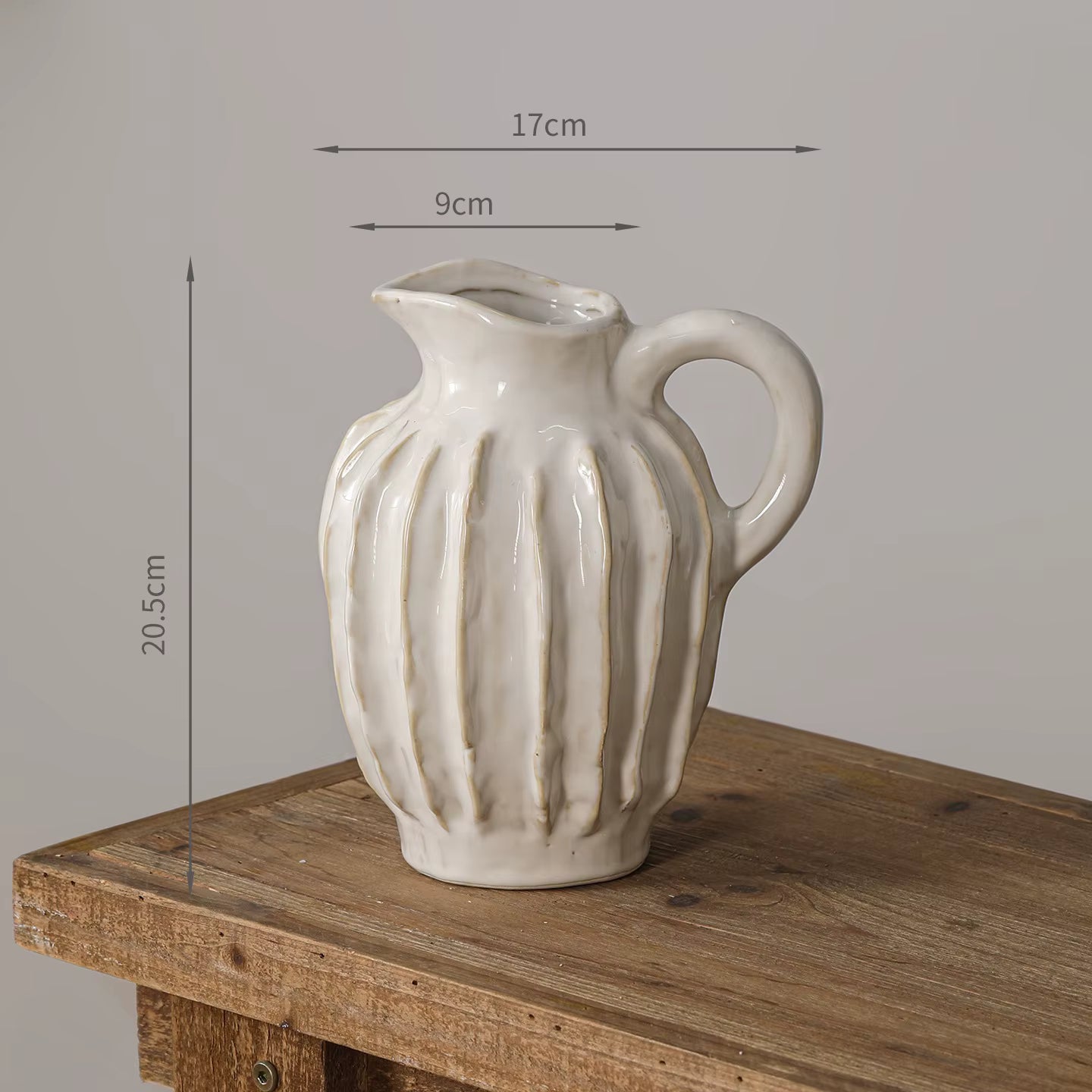 White ceramic pitcher with ribbed texture on a wooden surface, measurements indicated.