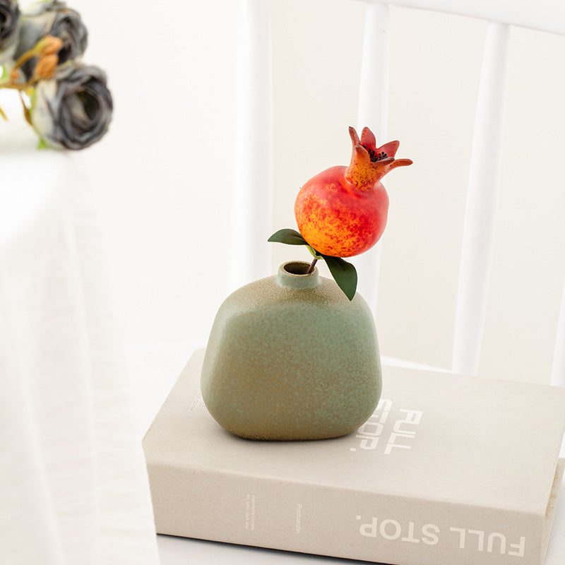 Small green vase with a decorative fox on top of a book