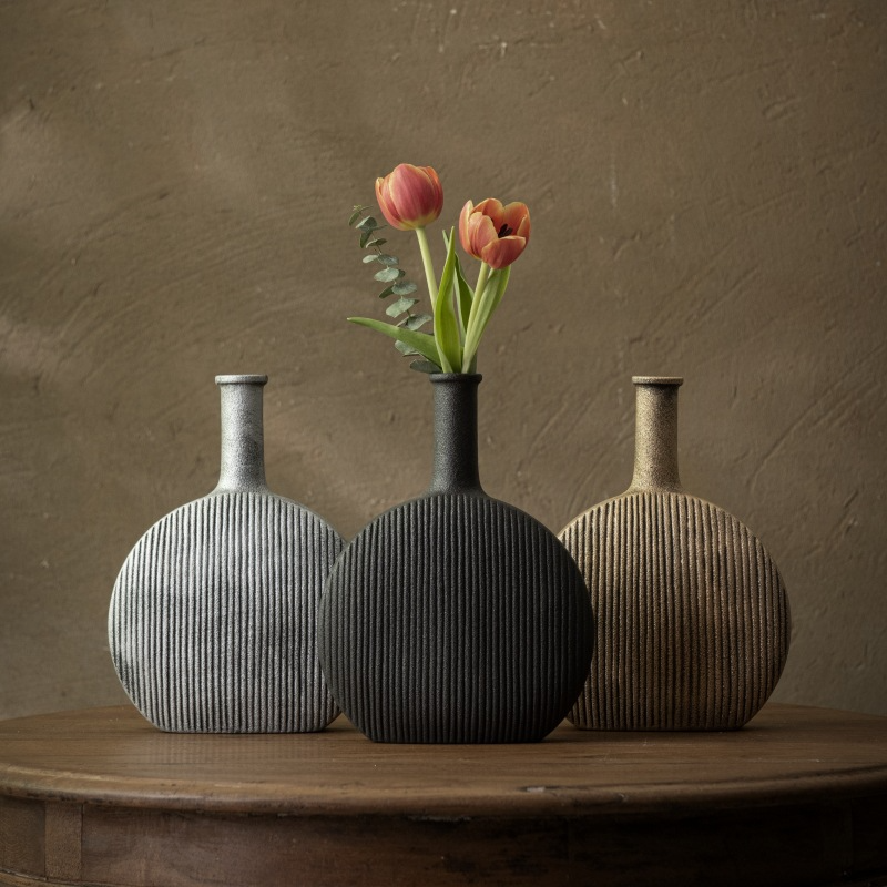 Three textured vases on a wooden surface with a brown background