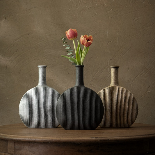 Three textured vases on a wooden surface with a brown background