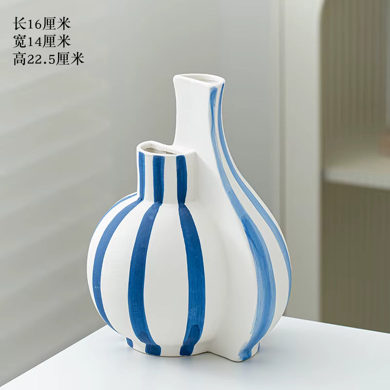 White vase with blue stripes on a white surface