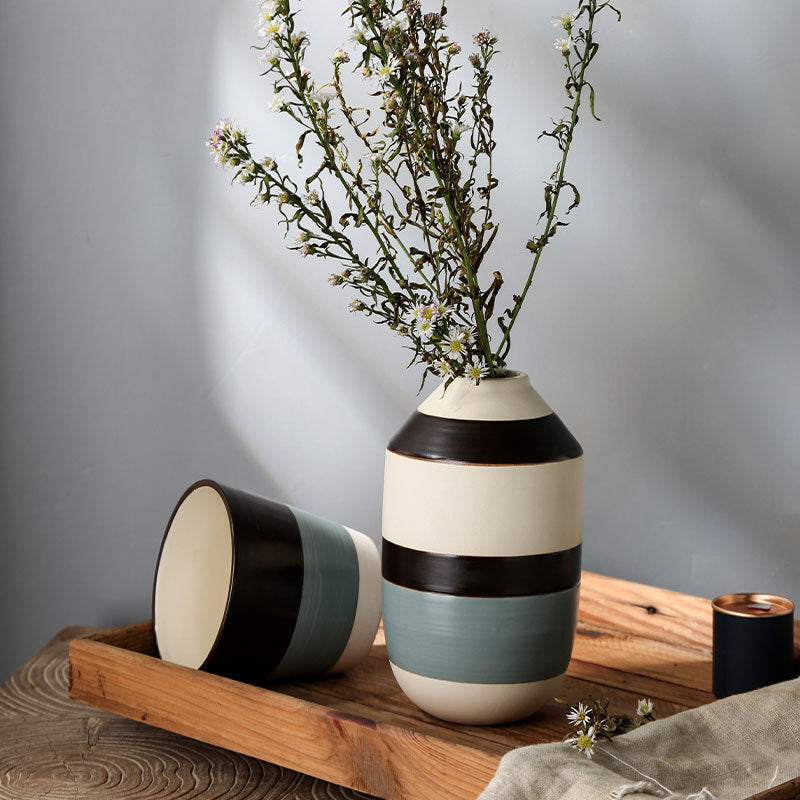 Two ceramic vases with striped design on a wooden tray against a gray background