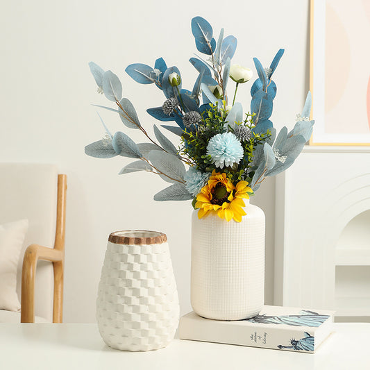 Decorative arrangement of flowers in a white vase on a table with a light background