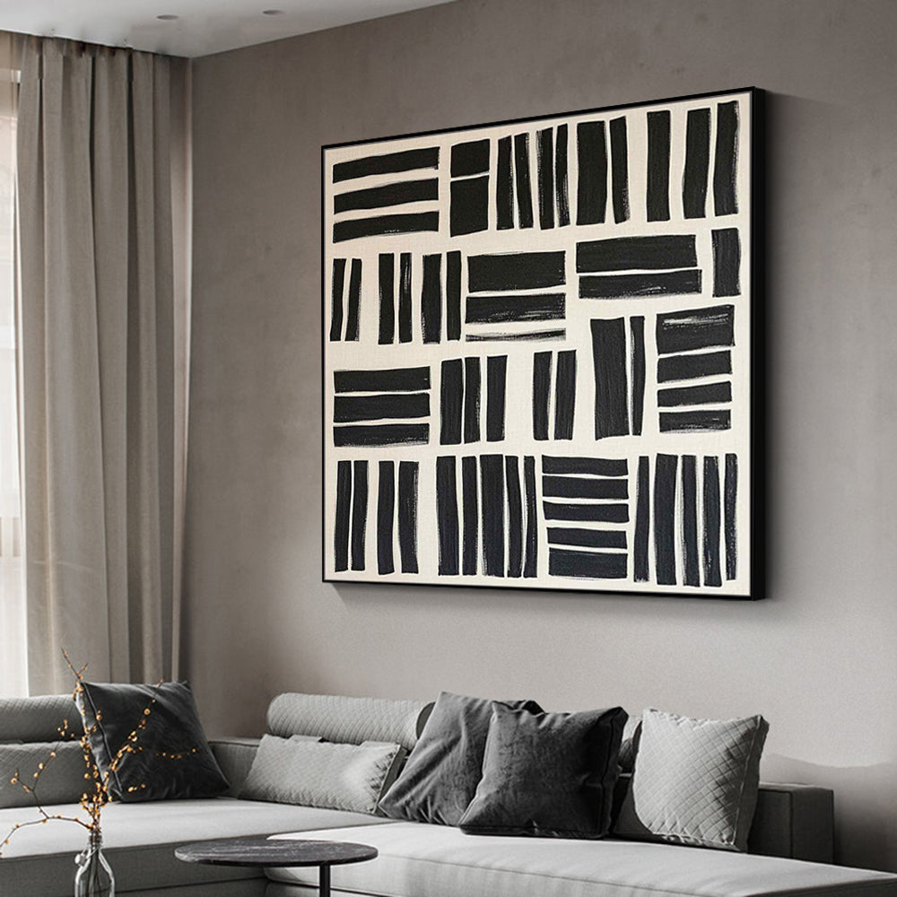 Abstract black and white painting on a wall above a sofa in a living room.