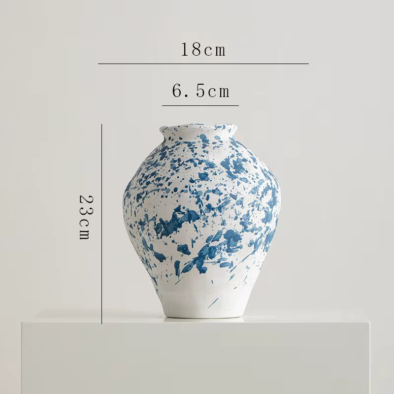 Ceramic vase with blue splatter design and measurements on a light gray background