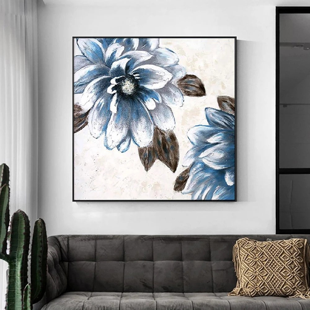 Floral artwork with blue flowers in a black frame on a wall above a sofa.