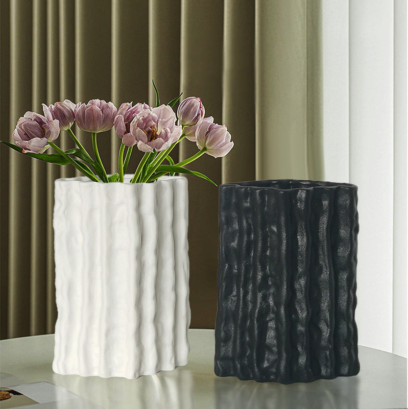 Two textured vases, one white and one black, with pink tulips on a neutral background.
