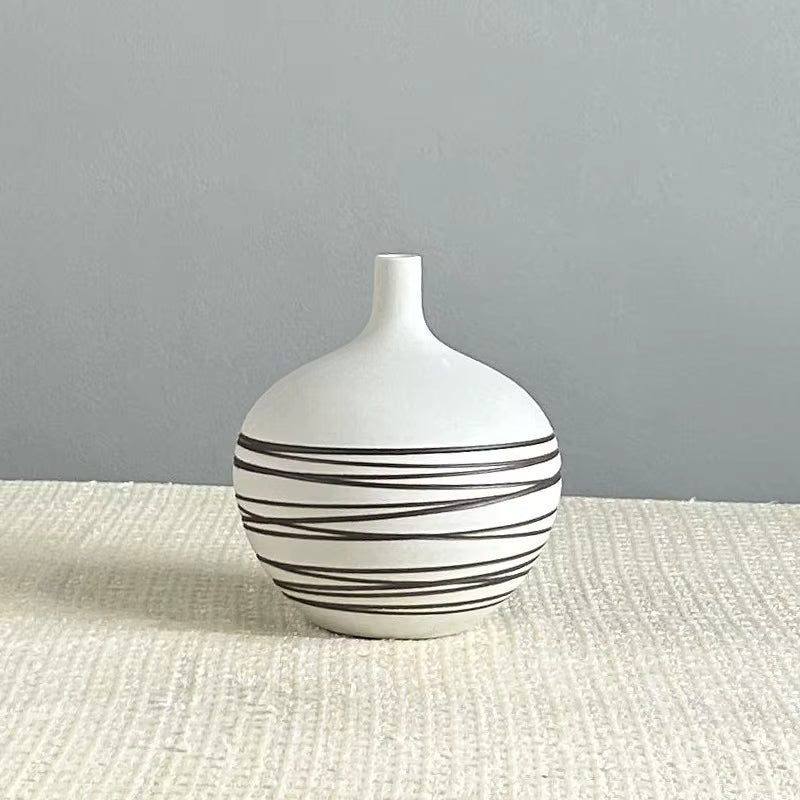 White vase with black stripes on a textured surface and gray background