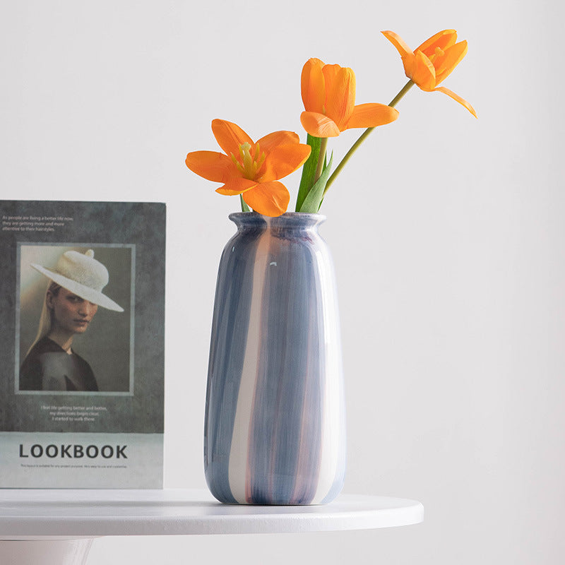 Blue and white striped vase with orange flowers on a white surface next to a 'LOOKBOOK' magazine.