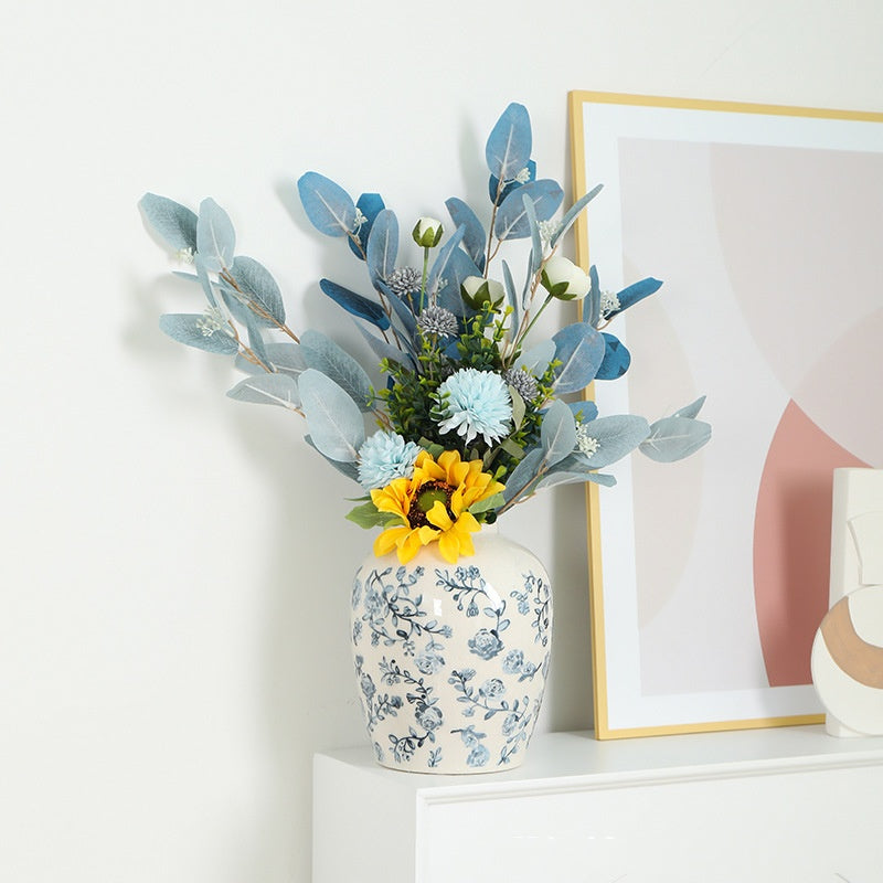 Decorative vase with flowers on a shelf next to a framed picture