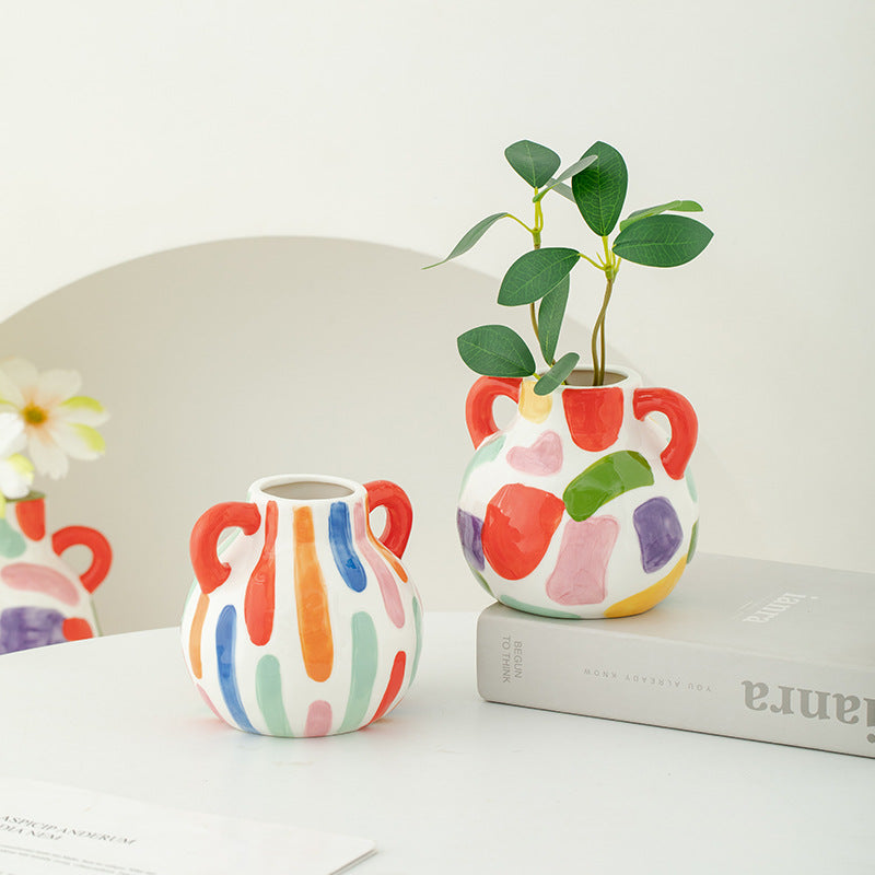 Colorful ceramic vases with abstract patterns on a white surface.