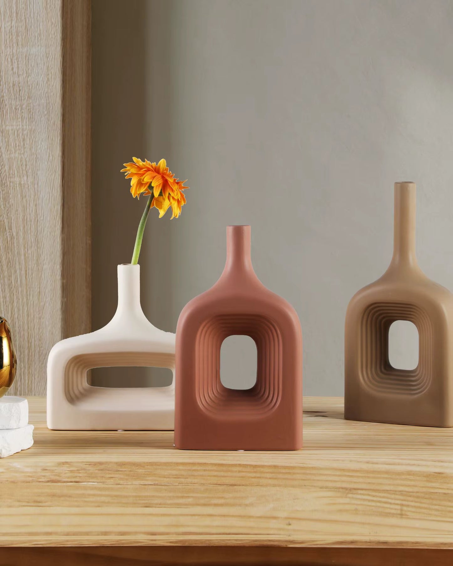 Three modern ceramic vases on a wooden surface with a neutral background