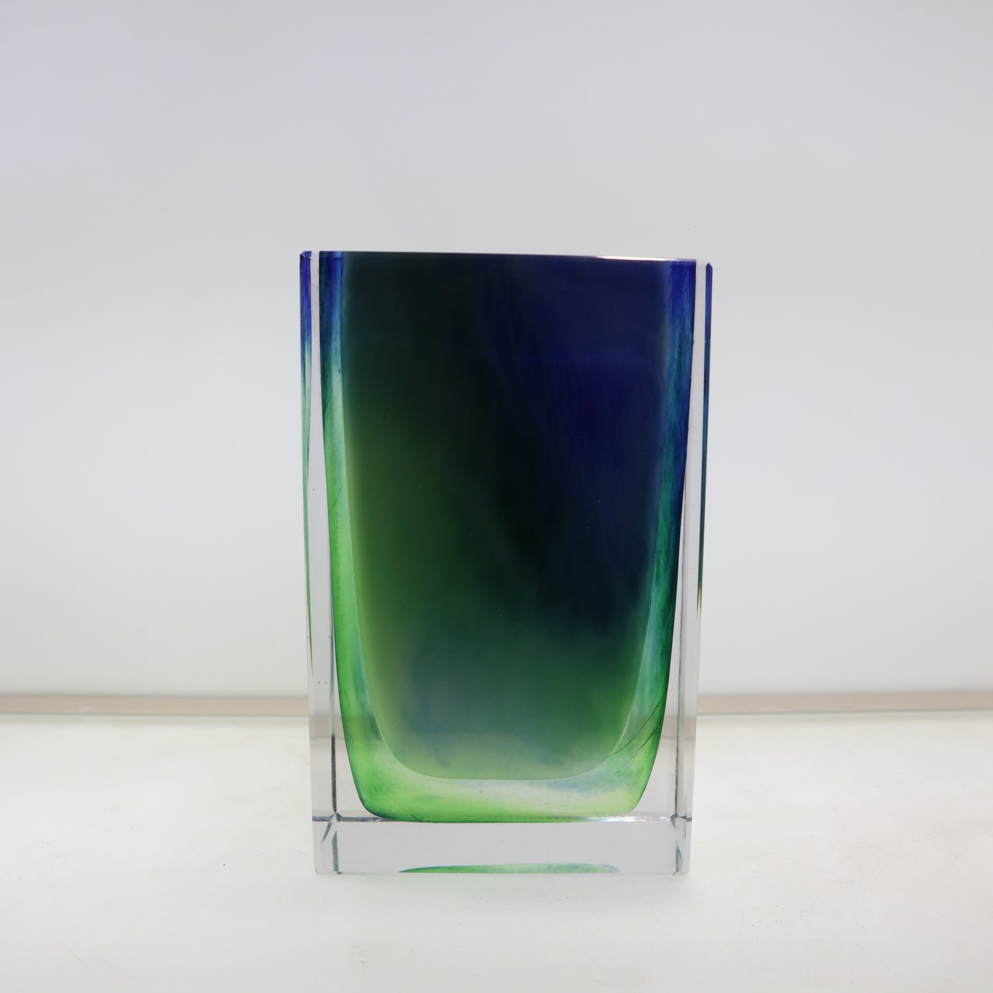 Glass vase with blue and green gradient on a white background