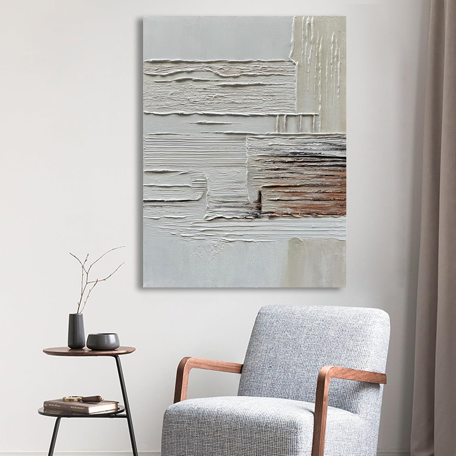 Abstract painting on a wall above a gray armchair in a room.